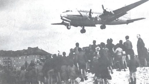Mokiniai stebi amerikiečių transporto lėktuvo skrydi i Berlyną. 1948 m. Sovietų Sąjungos pastangomis buvo užblokuotas Vakarų Berlyno aprūpinimas. Tik Vakarų pagalba privertė nutraukti blokadą. Oro tiltu buvo pergabenta 1,7 mln. tonų krovinių, atlikta 280 tūkst. skrydžių